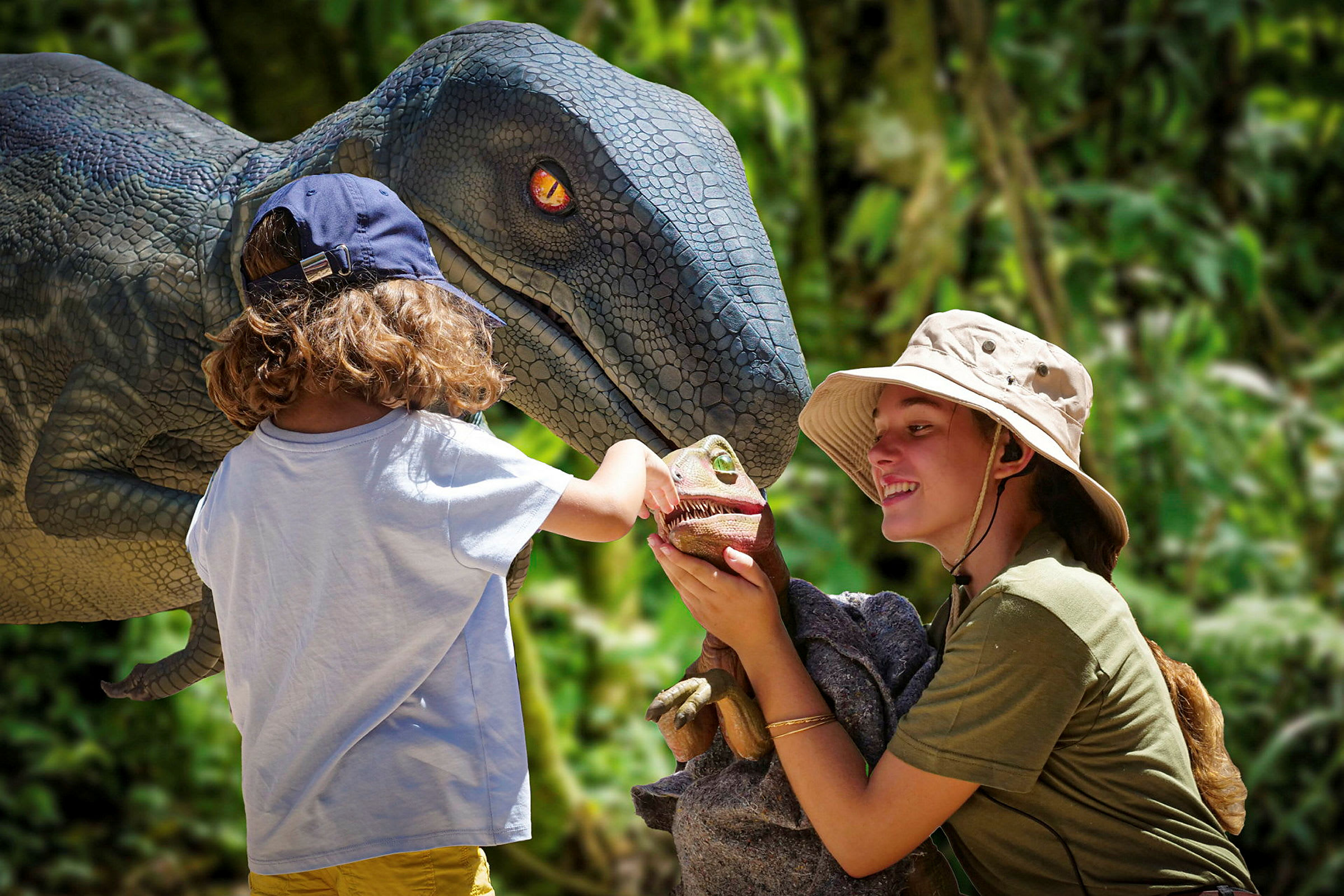 Et barn står foran en model af en dinosaur og et mindre legetøjsdyr i et naturområde. (AI-genereret tekst)
