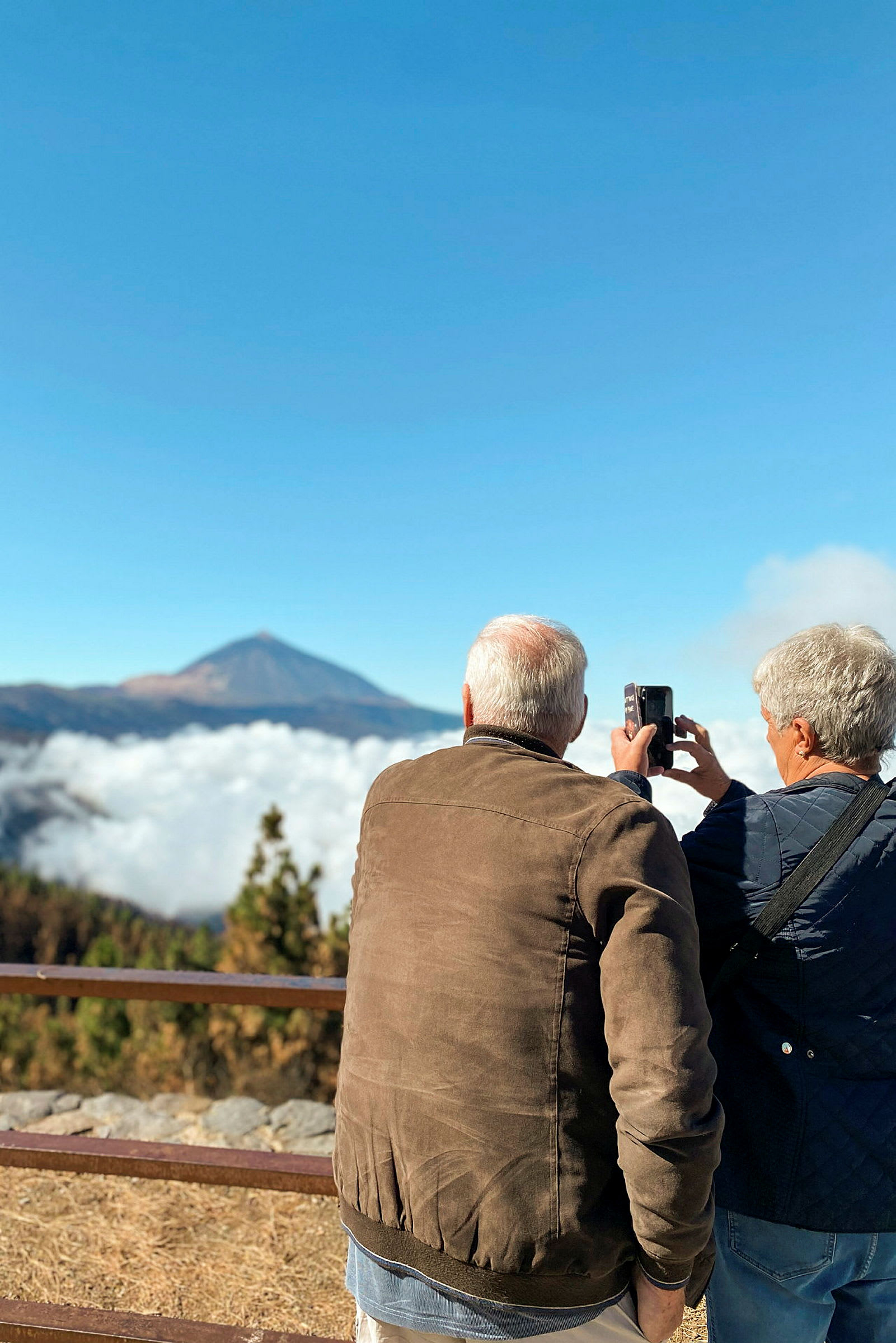 To personer fotograferer udsigten med bjerge og skyer. (AI-genereret tekst)