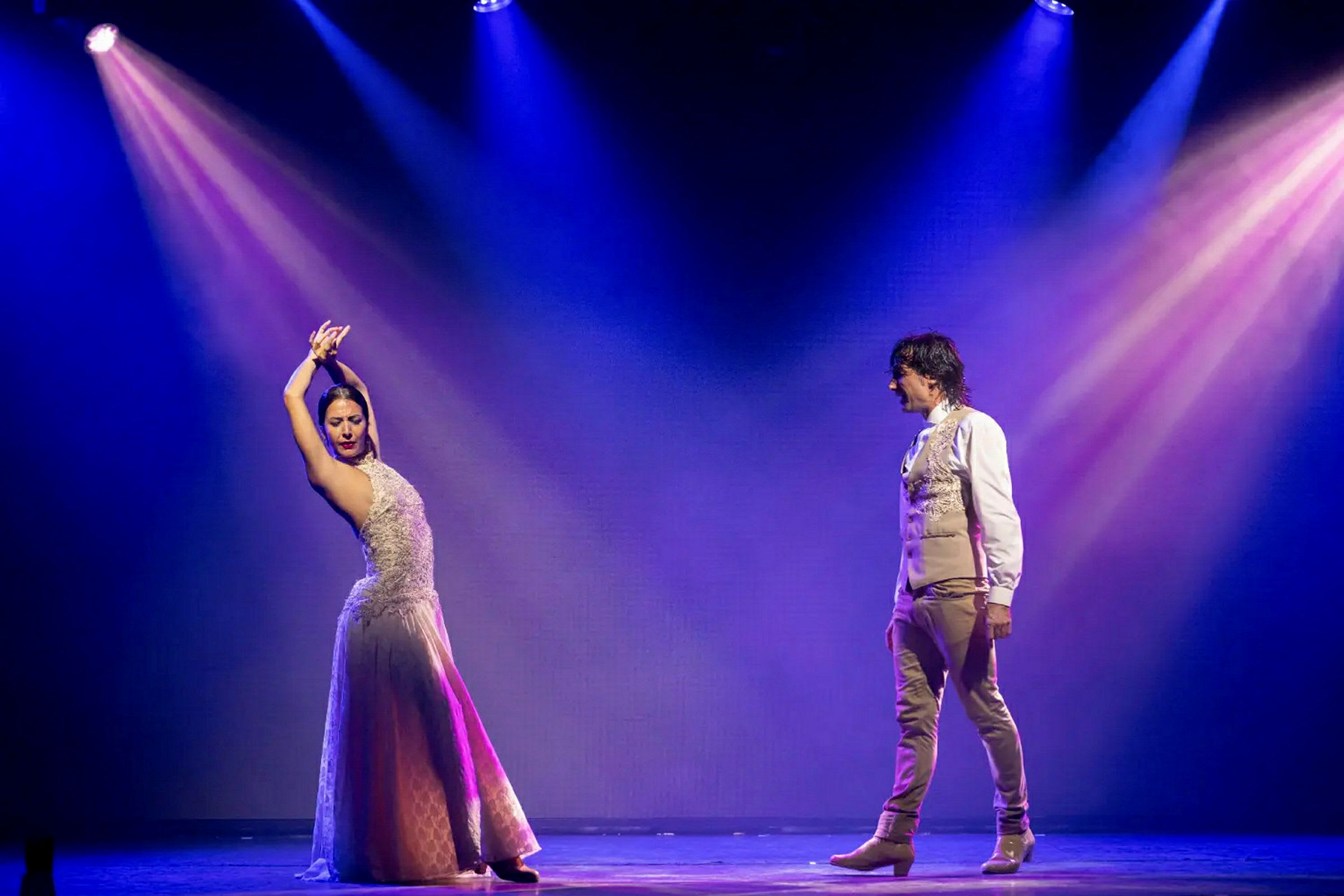 To personer danser på en scene med farverige projektører. (AI-genereret tekst)