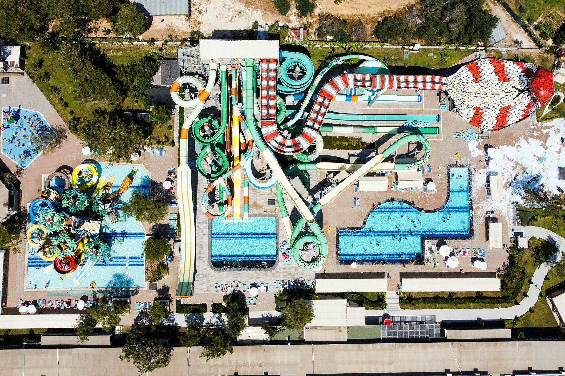 Luftfoto af en vandpark med flere vandrutsjebaner og poolområder. (AI-genereret tekst)