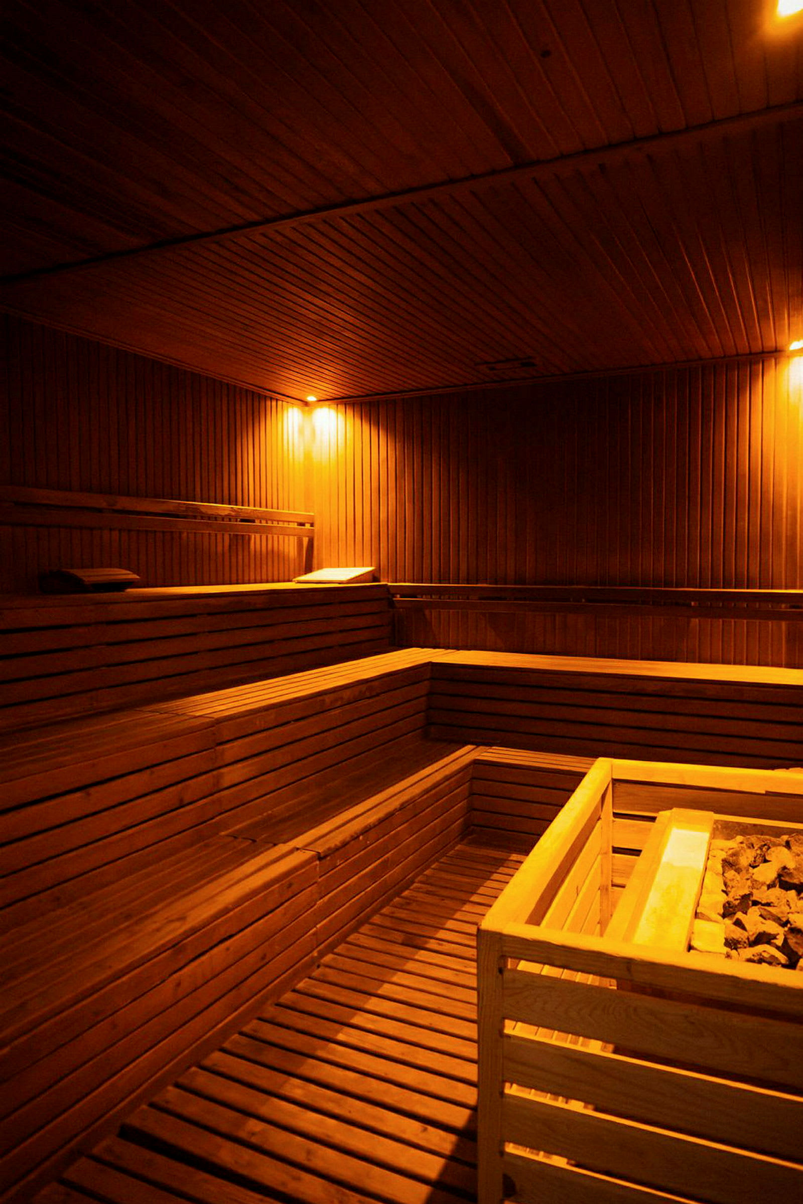 Et rum med træindretning, sauna bænke og en centralt placeret saunaovn. (AI-genereret tekst)