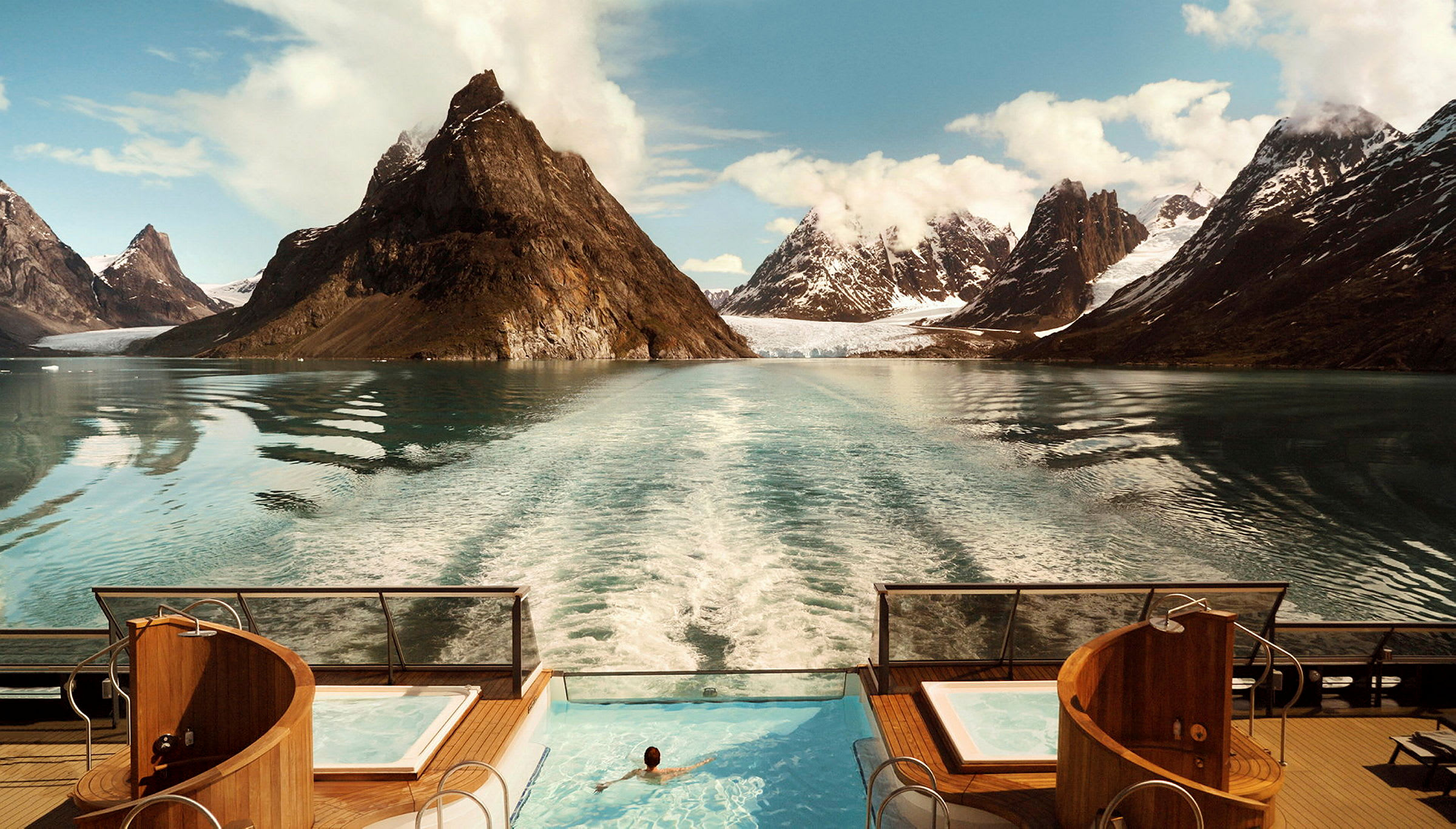 En pool ombord på en båd med udsigt over et fjordlandskab med høje bjerge. (AI-genereret tekst)